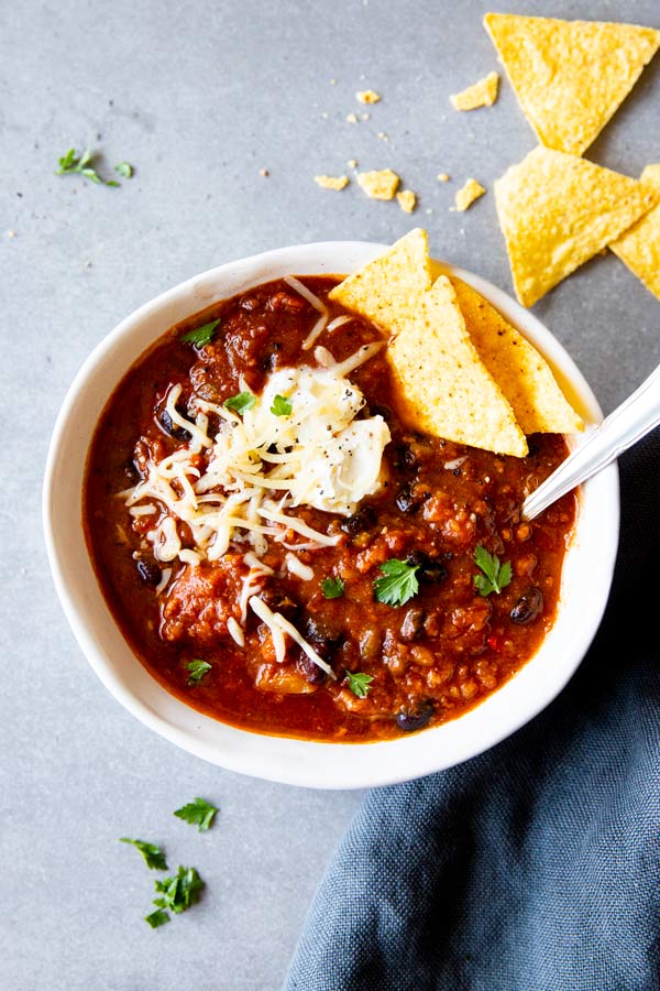instant pot pumpkin chili in a white bowl with toppings and corn chips