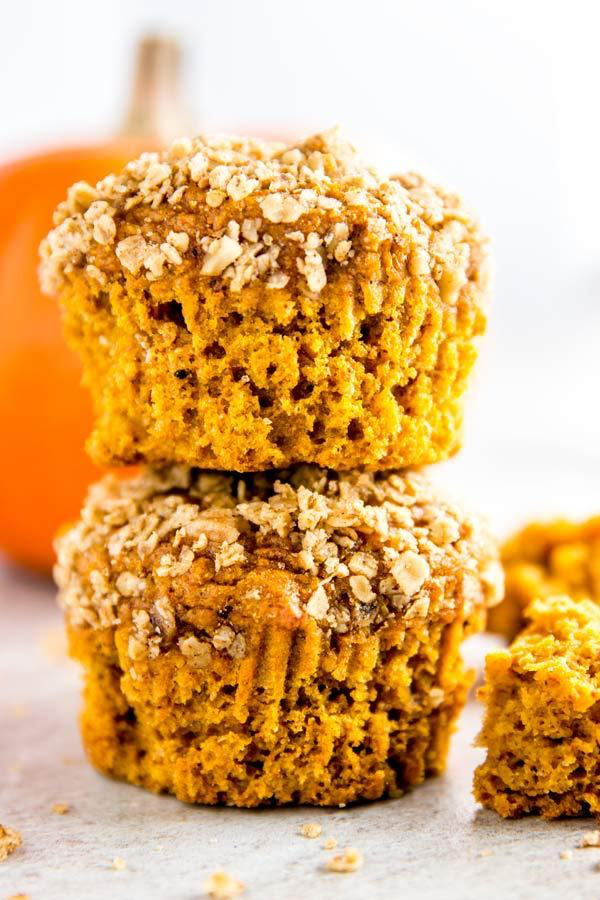 stack of healthy pumpkin muffins in front of a small orange pumpkin
