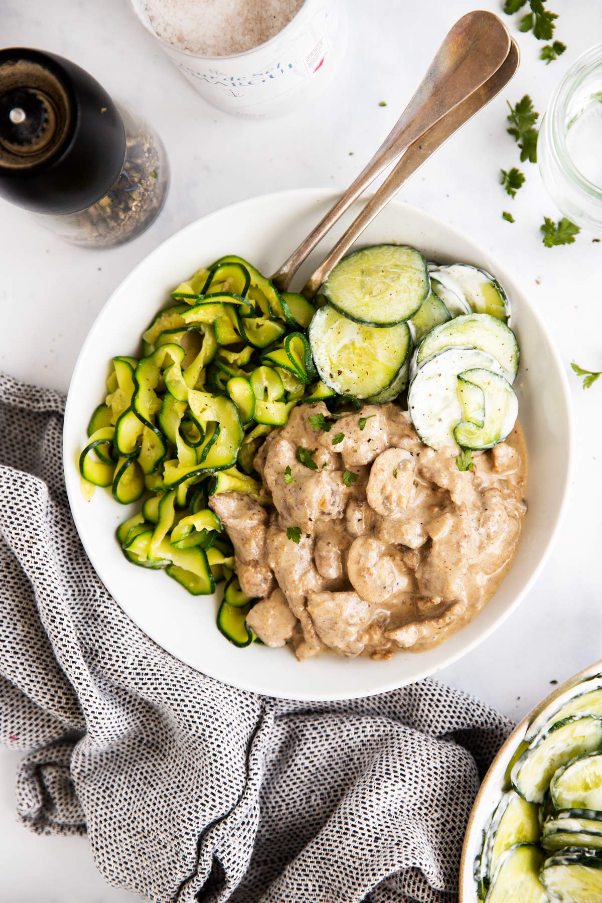top down view on a plate with low carb stroganoff, zucchini ribbons and cucumber salad
