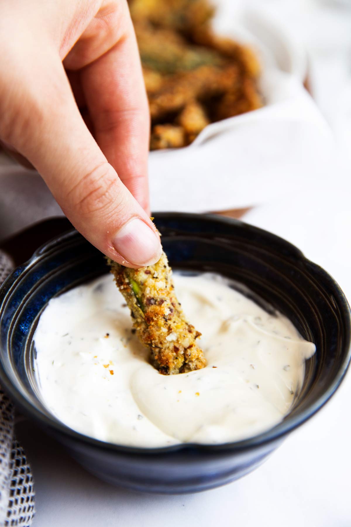 dipping a healthy zucchini fry into sour cream dip