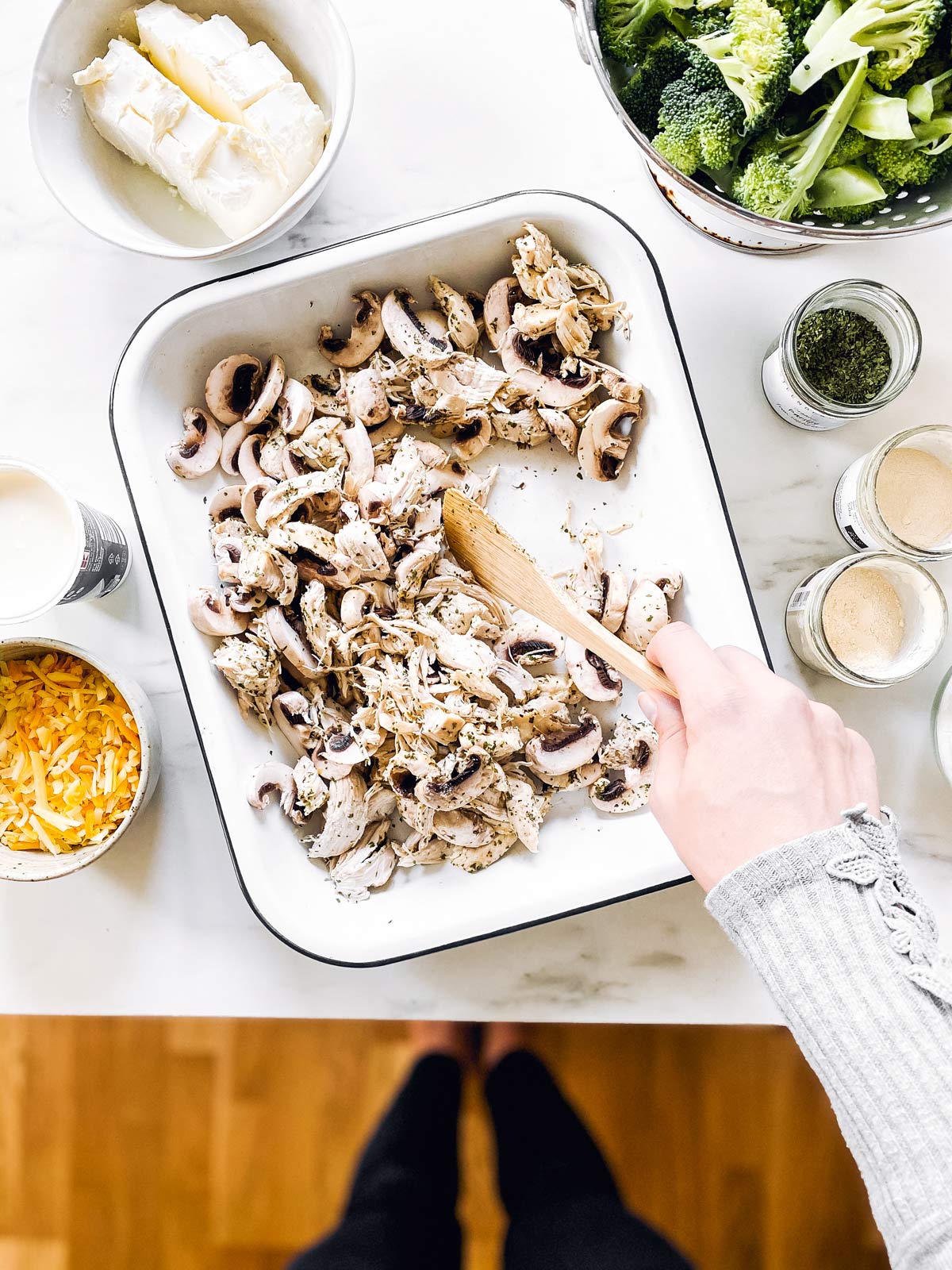 female hand stirring chicken and mushrooms in casserole dish