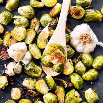 roasted Brussels sprouts on a sheet pan with a wooden spoon