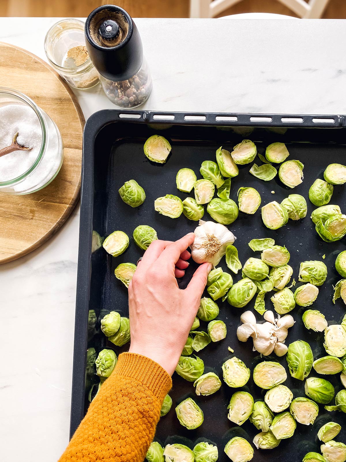 placing garlic on a pan with Brussels sprouts