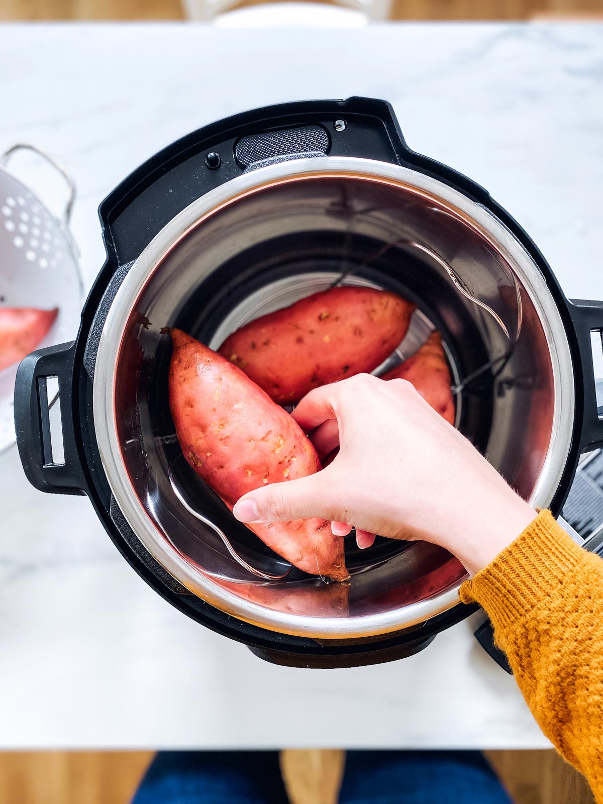 female hand placing sweet potato in instant pot