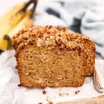 frontal view of sliced banana bread in front of bunch of bananas