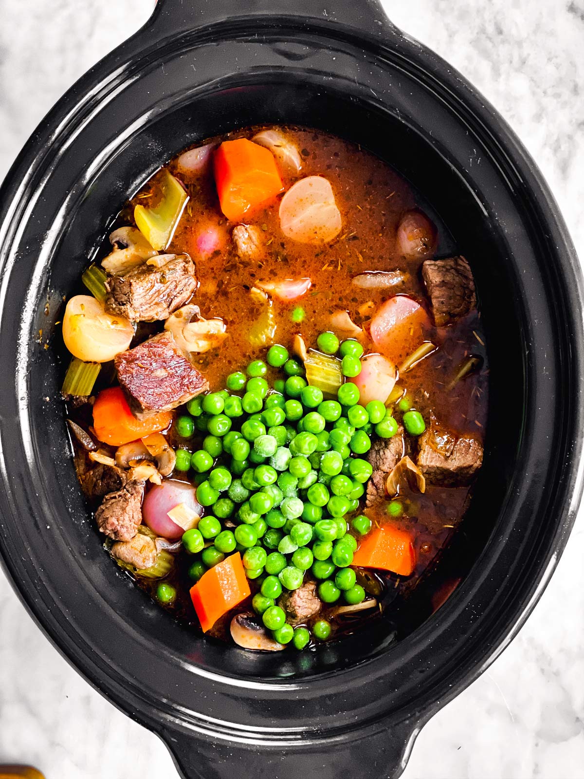 slow cooker with beef stew and peas