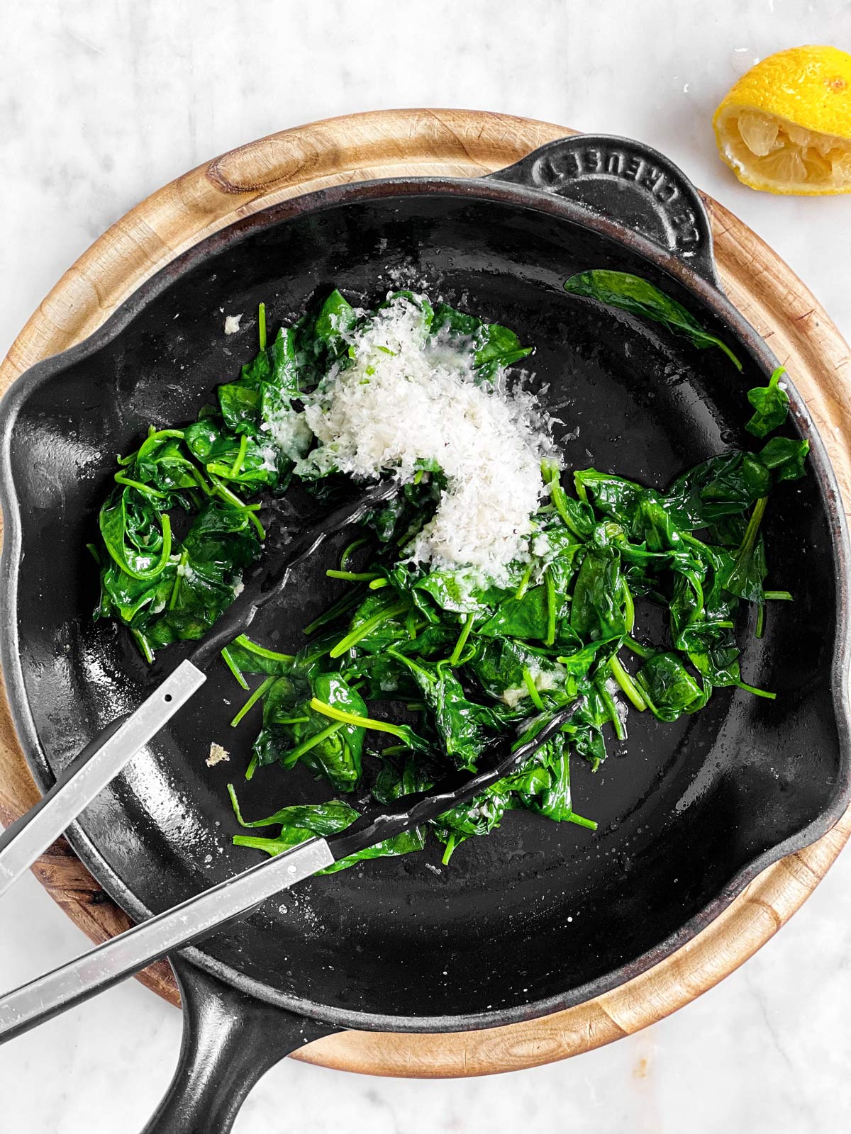cast iron skillet with wilted spinach, parmesan cheese and lemon juice
