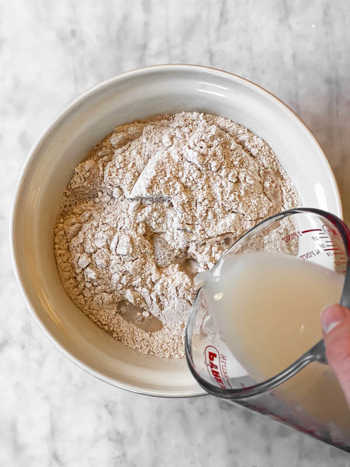 pouring yeast mixture into bowl with flour