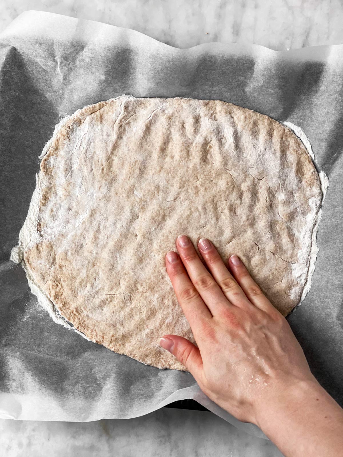 female hand pressing pizza crust into circle